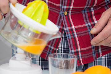 man making orange juice with juicer