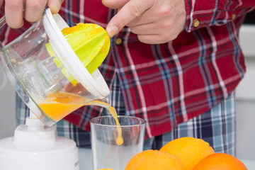 man making orange juice with juicer