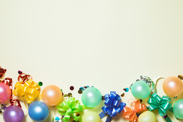 Birthday party bright pastel background with streamers, confetti, balloons on yellow backround. Top view, flat lay