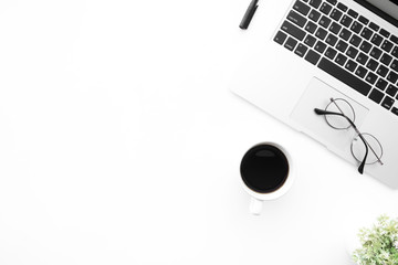White office desk table with laptop computer, cup of coffee and supplies. Top view with copy space, flat lay.
