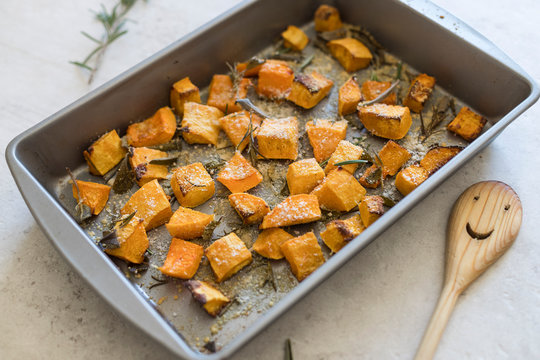 Baking sheet/frying pan with oven baked butternut squash/pumpkin with sage leaves and shredded parmesan cheese. Shallow space, close up, background. 