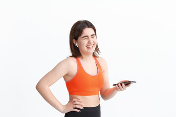 Fototapeta na wymiar Young fitness woman posing isolated on a white background listening to music with wireless headphones.