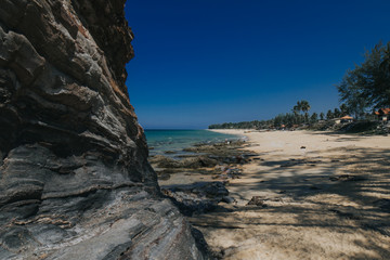 Fototapeta na wymiar Beautiful tropical island beach scenery with palm trees,nature rock formation and blue sky background.