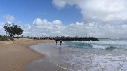 Buddina, Australia - Apr 21, 2019. People relaxing on Buddina Beach breakwall (Sunshine Coast, Queensland, Australia) on a sunny but cloudy day.