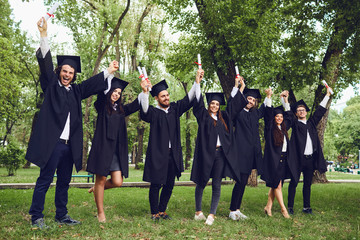 Students graduates with scrolls of diplomas up