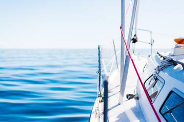 White yacht sailing on a clear sunny day. A view from the deck to the bow, mast and sails. Norway