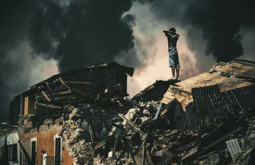 Homeless little boy watching destroyed houses and bombarded city.