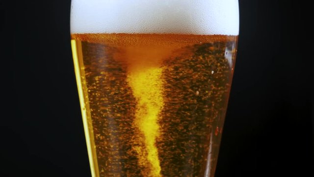 bubbles in the beer in the glass. the beer is poured into a beer glass and it flows in foam in a glass