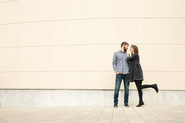 Trendy hipster couple near light wall outdoors