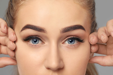 Fototapeta premium Young woman with beautiful eyebrows on grey background, closeup