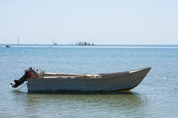 Old fishing boat with motor on the coast and in the sea water in summer.