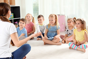 Kindergarten teacher and little children indoors. Learning and playing