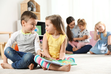 Cute little children reading book together indoors, space for text. Learning and playing