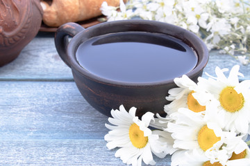 Next to the white flowers of chamomile is a cup of tea