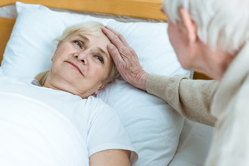 partial view of senior sick woman with husband in clinic