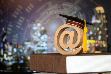 Education world knowledge ideas. Graduation cap, wood email address symbol on textbook, blur HUD...