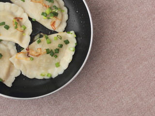 Closeup of pierogies in a pan. Traditional Polish dish prepared on a frying pan and topped with green onion.