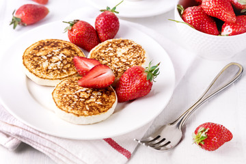 ThreeTasty Homemade Cottage Cheese Pancakes with Strawberries on White Plate Tasty Healthy Diey Breakfast Breakfast Concept Horizontal
