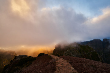 Sunset on mountain with gold sky and trail leading to clouds, pico de arieiro, Madeira