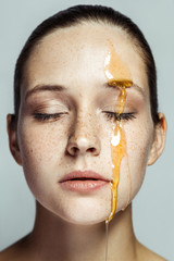Portrait of beautiful young brunette woman with freckles and honey on face with closed eyes and...