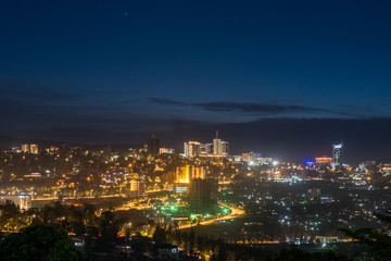 Kigali city centre skyline and surrounding areas lit up at night under a dark blue sky