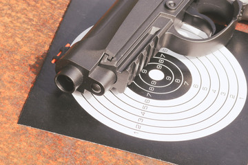 Black pistol gun with target on the metal grunge background.