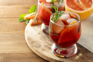 Grapefruit and rosemary gin cocktail, refreshing summer, cold pink drink. Wooden table.