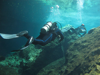Two divers exploring the cenotes in Mexico - Underwater at cenote Chac Mool in the Riviera Maya, Mexico.