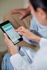 Close-up of female doctor holding mobile phone and examining the results of her patient in special...