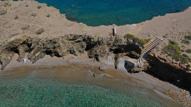 Aerial drone photo of iconic deep turquoise beach of Latinaki with crystal clear sea and rocky sea shore forming small caves, Folegandros island, Cyclades, Greece