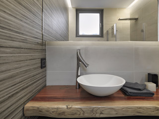 Fototapeta na wymiar interior shot of a modern bathroom in the foreground the counter top washbasin on the wooden top