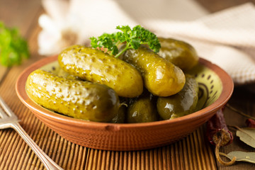 Marinated cucumbers. Pickles veggies in bowl, wooden table.