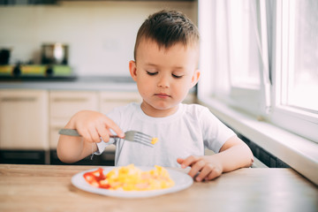 child day in the kitchen eating an omelet with sausage and ketchup