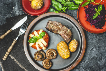 grilled autumn dinner, steak, baked tomato with cheese, baked potatoes with garlic and mushrooms