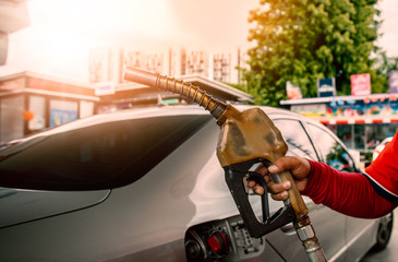 Naklejka premium Hand holding gas nozzle in gas station for car refueling