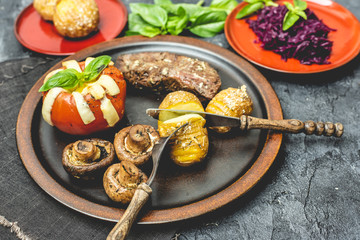 grilled autumn dinner, steak, baked tomato with cheese, baked potatoes with garlic and mushrooms