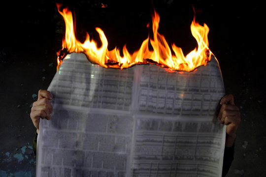 man holding burned newspaper burning newspaper