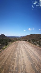 Fototapeta premium Dust road winding through hills and mountains