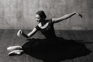 Ballerina in ballroom. Ballet dancer in studio. Black and white monochrome. Sitting slim ballerina.