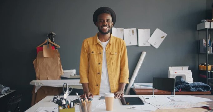 Portrait of handsome African American designer smiling standing at work looking at camera enjoying small business. Fashion design, job and millennials concept.
