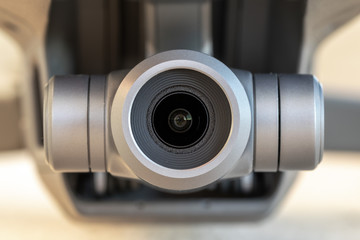 Macro close-up of a 3 axis electronic stabilized digital camera gimbal mounted on a modern remote controlled quadcopter drone. Selective focus on the camera lens.