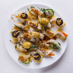 Salted herring on skewers with cheese and olives on plate
