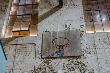 Decaying basketball hoop in a forgotten gymnasium of an abandoned school