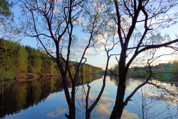 Fototapeta na wymiar Beautiful sunset on the forest lake. Clouds reflected in water.