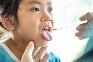 Professional Doctor dentist examining oral teeth throat hygiene care cute kid patient in hospital