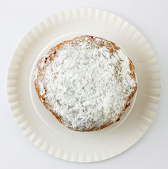 donut with icing sugar on paper plate