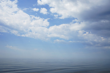 calm sea with a haze on a blue cloudy sky