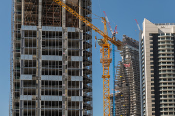 A yellow crane stands on a construction site where several skyscrapers are being built.
