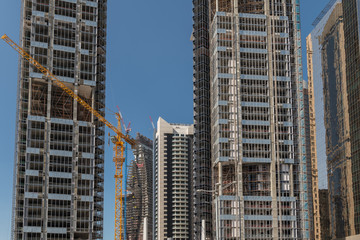 Newly constructed skyscrapers on a construction site, a yellow crane is in the middle