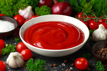 Homemade ketchup sauce in white bowl with vegetables and herbs